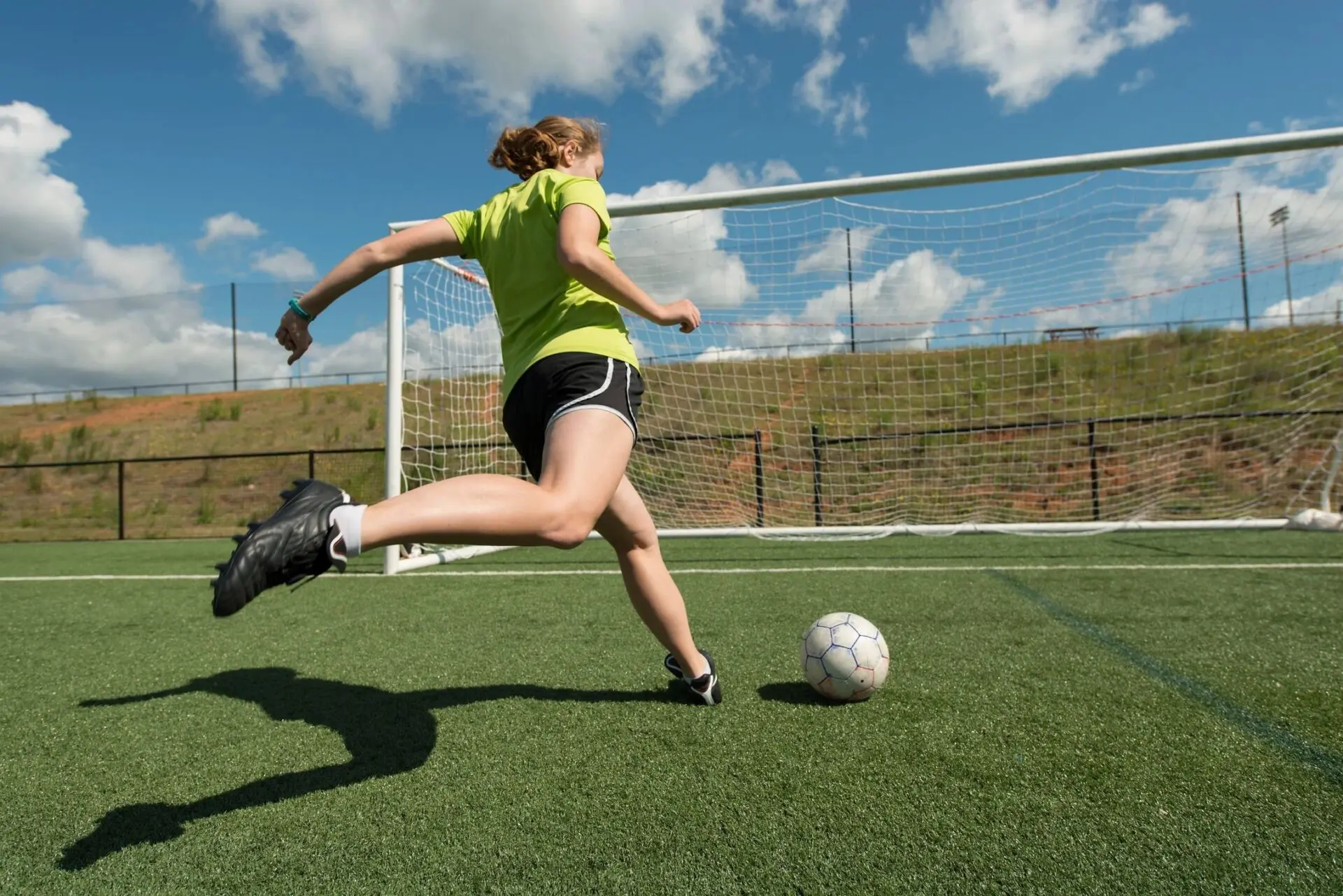 A teenage soccer player kicking the ball